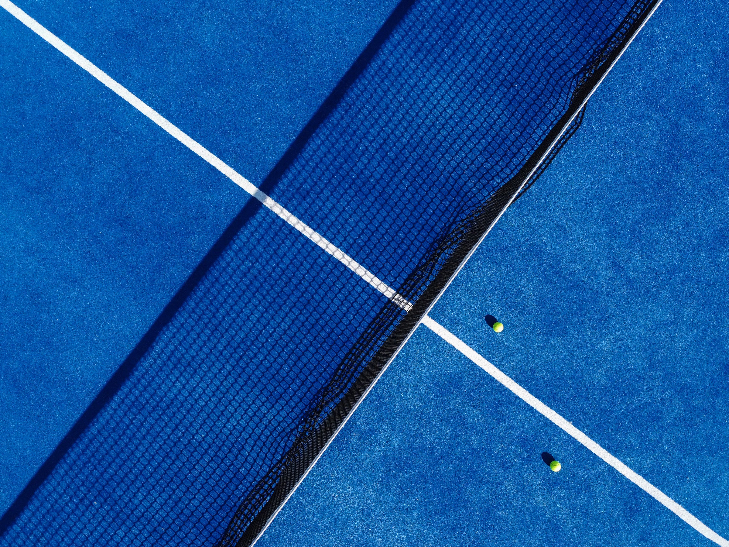 Plue padel court with two balls near the center net
